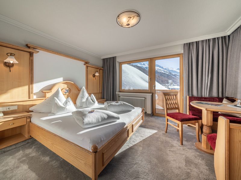 Helles Doppelzimmer im Burghotel Alpenglühn mit Bergblick, Holzmöbeln, Sitzecke und Zugang zum Balkon